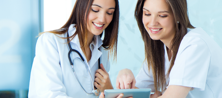 Two nurses with long brown hair looking at a tablet device