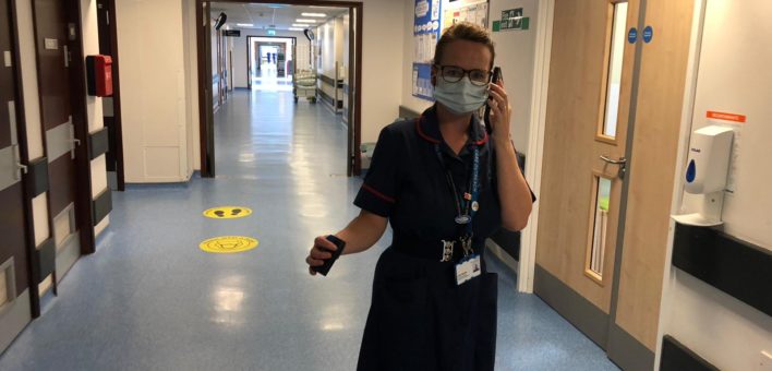 Photograph of Lisa Booth walking down a hospital corridor using a mobile phone