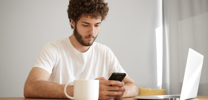 Generic photograph of focused young bearded male looking at information online