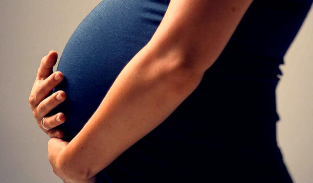 An image of a pregnant person nursing their bump.