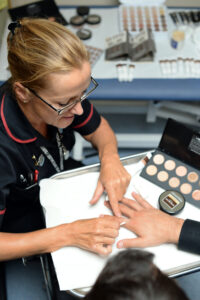 A consultant applying skin camouflage to a patients hand.