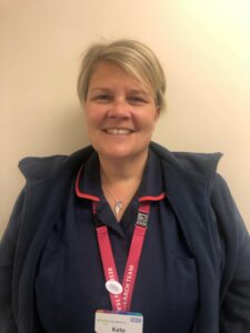 Woman in nurses uniform with red lanyard looking at camera