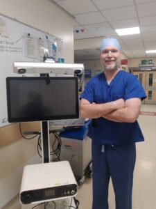 Man in theatre scrubs standing by computer