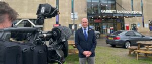 Chief Executive Nick Hulme standing in front of the Garret Anderson Centre with a reporters camera ready to record him. 