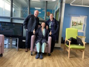 man and nurse standing by man in hospital sitting in hospital chair