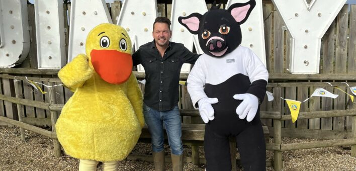 Jimmy stands between the Puddles the Duck mascot and the Rosie Pig mascot