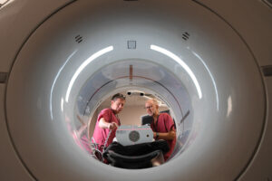 two men looking down a large circular tube. both in clinical uniforms