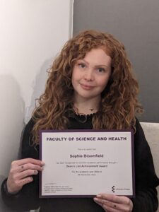 Close up of woman with red curly hair holding a certificate