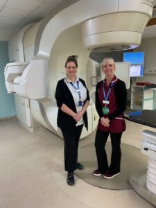 Two clinicians standing by large white machine