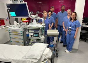 Hospital staff in a room with equipment and a hospital bed
