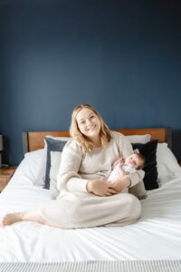 Mum holding newborn on bed looking at camera
