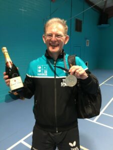 man in sports gear holding medal and bottle of champagne
