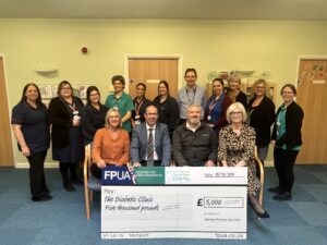 A group of people present a large charity cheque to hospital staff