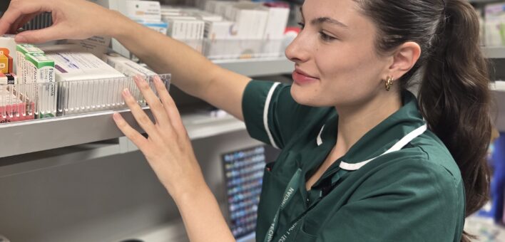 Pharmacy technician Emily Southall selects medication from a shelf.