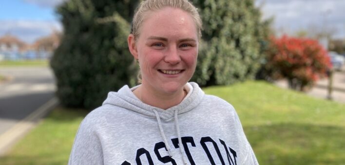 A photograph of Lucy Allerton, wearting a grey hoodie and smiling at the camera. She has blonde hair