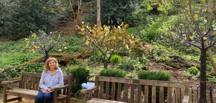 Ali Brett sits on a bench next to the Tree of Remembrance