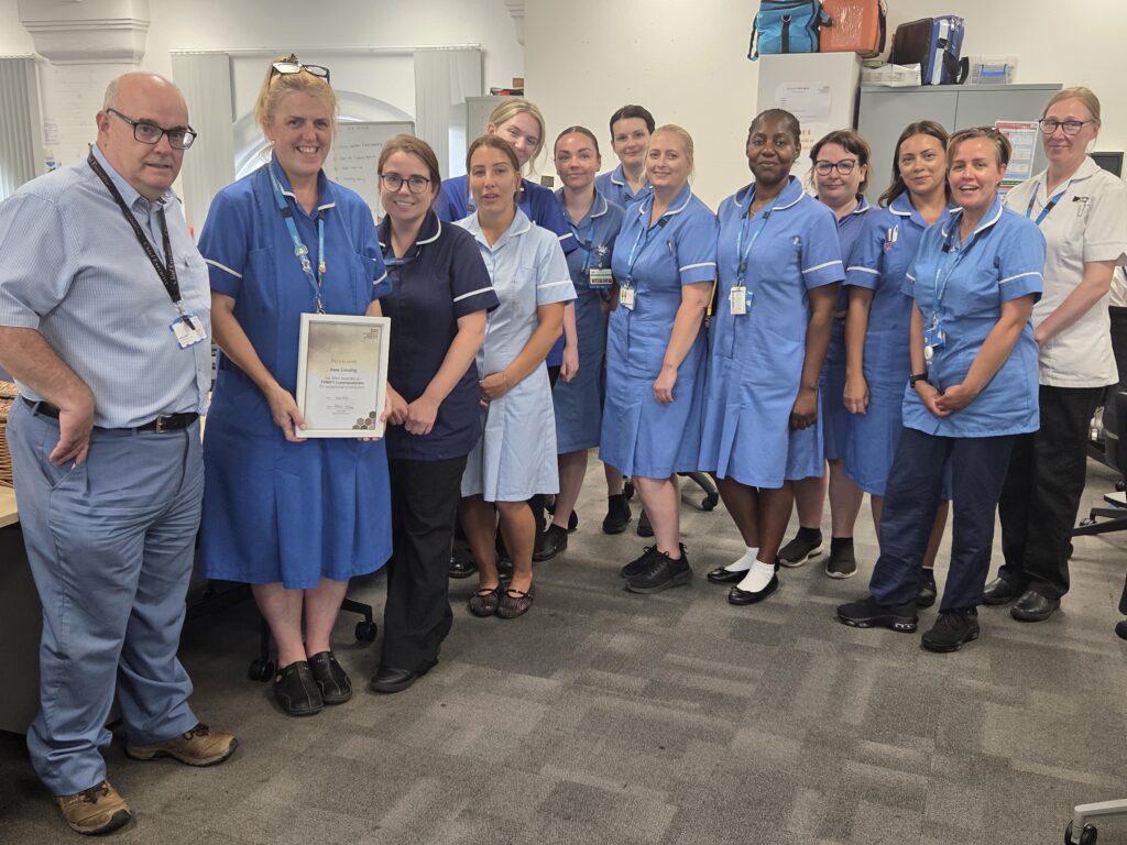 Anna celebrates her award stood with ESNEFT interim chief executive Adrian Marr, lead community nurse Laura Ward, and members of the community team.