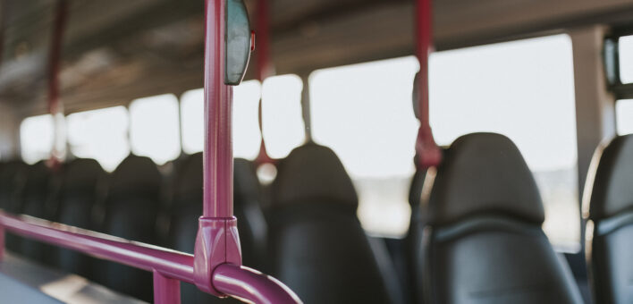 Top deck of a bus bell button in foreground and empty seats out of focus in background